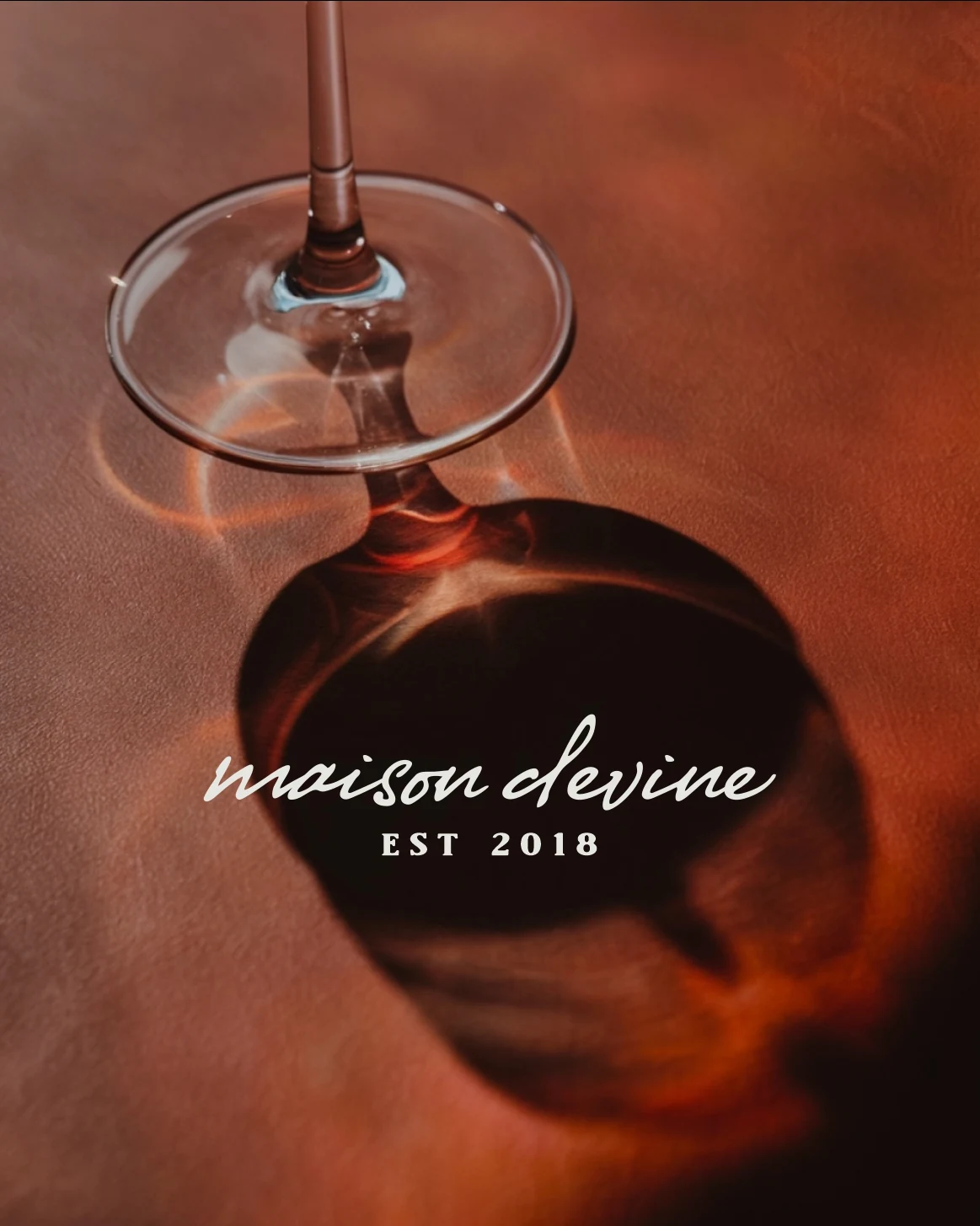Logotipo de Maison Devine aplicado sobre una copa de vino
